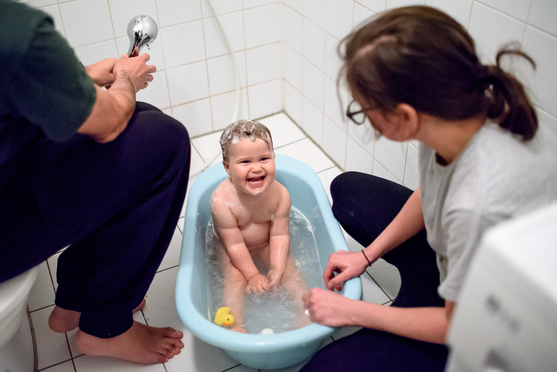 little girl getting a bath from parents